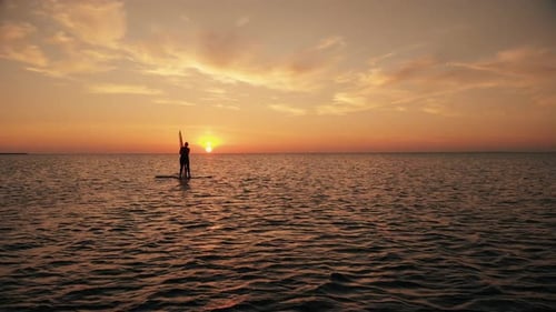 Woman Lifting Up Sail of Windsurfing Training on Calm Ocean