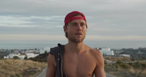 Shirtless Man In Red Cap Walking Along Road