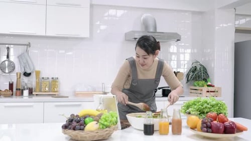 Woman Preparing Salad in Bright Kitchen