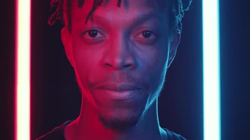Apuesto hombre afroamericano sonriendo a la cámara con luz de neón