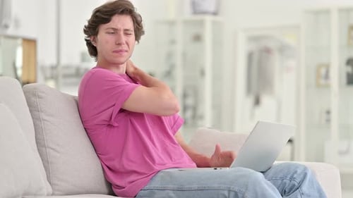 Young Adult Typing on Laptop Stretches Neck