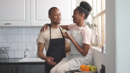 Affectionate Couple Sharing Apple in Bright Kitchen