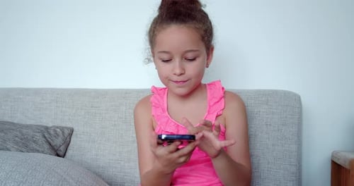 Girl Using Smartphone on Sofa at Home