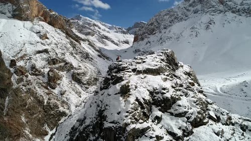 Lone Hiker Stands Atop Snowy Mountain Peak