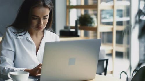 Happy Freelance Woman Working Remotely From Her Computer in Modern Cafe