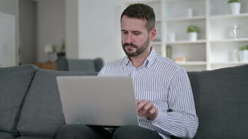 Man Finishes Working on Laptop in Living Room