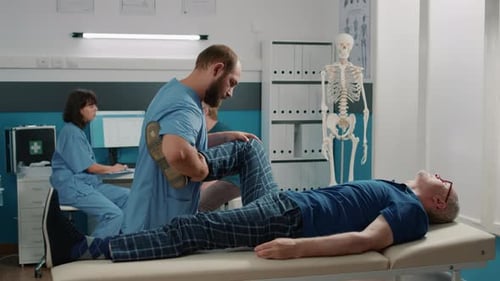 Physical Therapist Stretching Patient's Leg in Office