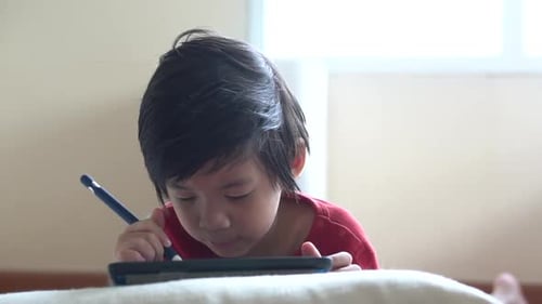 Child Draws on Tablet with Stylus Indoors
