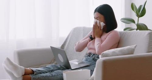 Young Woman with Cold Using Laptop at Home