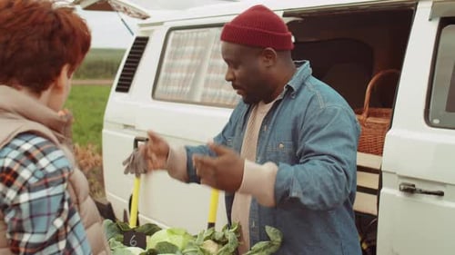 Young Women Buying Fresh Vegetables from African American Farmer