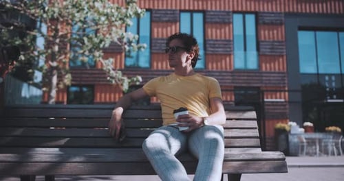 Man sits on park bench while holding coffee