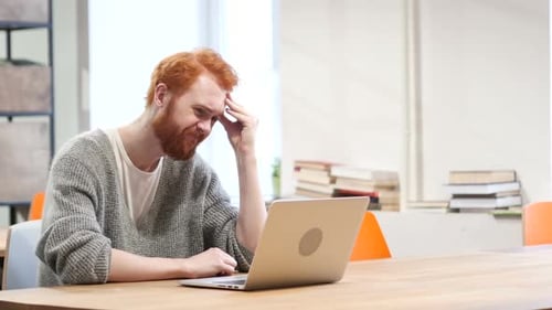 Frustrated Man Working at Laptop Computer Indoors