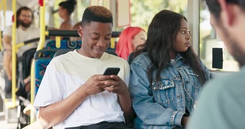 Young Man Uses Phone on Bus Next to Friend