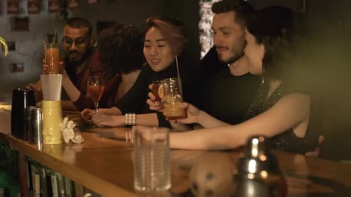 Des amis multiethniques qui tintent des verres au bar