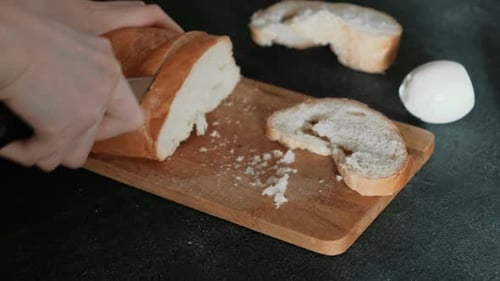 Person Slicing Fresh Bread on a Cutting Board