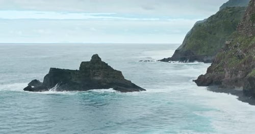 Steep Rocky Cliffs Covered with Moss and Vegetation Surrounded with High Tides
