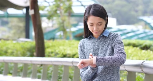 Young Woman Using Smart Watch in Urban Park