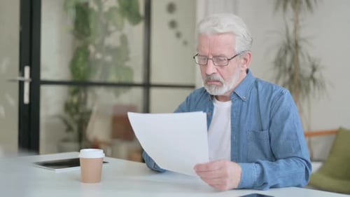 Senior Old Man Reading Documents in Office