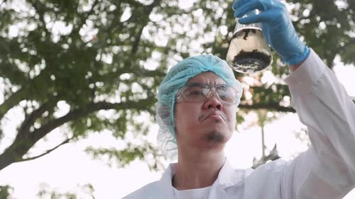 Scientist Inspecting Flask in Natural Setting