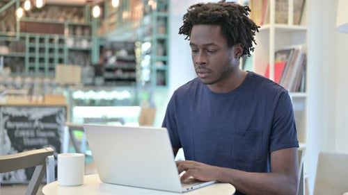 Afrikanischer Mann schließt Laptop und verlässt Café