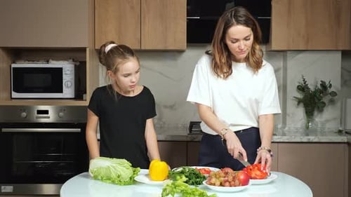 Teen Daughter Watches Mother Cutting Bell Pepper in Kitchen
