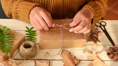 Hands Tying String Around Brown Paper Gift