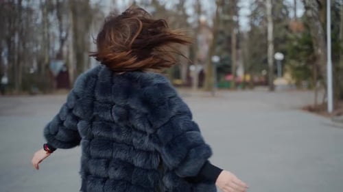 Stylish Woman in Fur Coat Strolling in Park