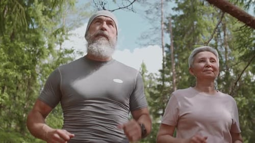 Mature Couple Jogging Through Forest Together