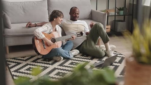 Woman Plays Guitar for Friend at Home