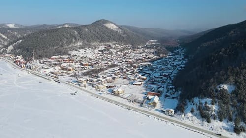 Flying over the highway at foot of hills. The shore of lake on clear winter day