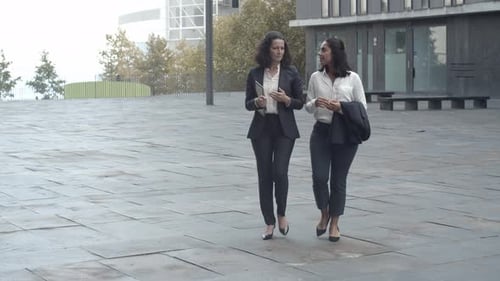 Businesswomen Walk and Talk Outside Building