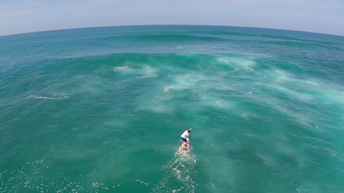 Aerial view of a man paddling while sup stand-up paddleboard surfing in Hawaii.