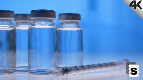 Clear Vials and Syringe on Blue Background