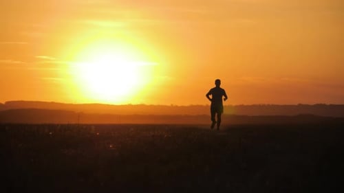 Person Running Across Field at Sunset