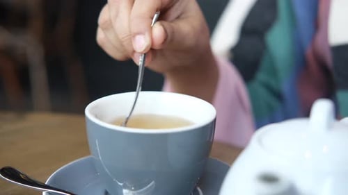 Person rührt grünen Tee mit Löffel