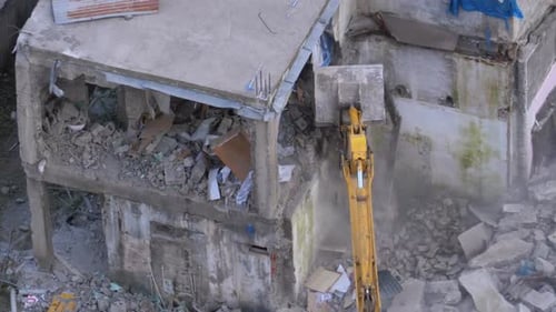 Destroying Old Concrete House Using Mechanical Arm of Bulldozer on Construction Site