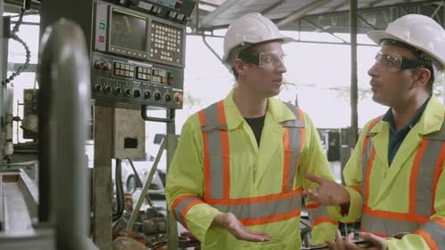 Engineers Discussing Industrial Machinery at Workplace