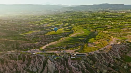 Hot air balloons fly over the mountainous landscape of Cappadocia, Turkey.