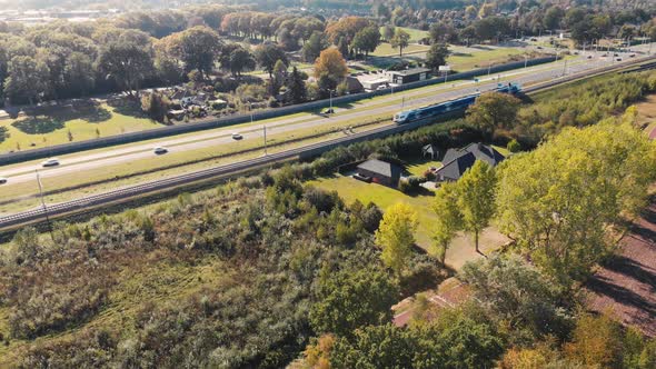 Public transport train passing a freeway through a rural surrounding ...