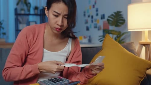 Lady feel stress worried with bill and invoice credit card calculating money on sofa at home night