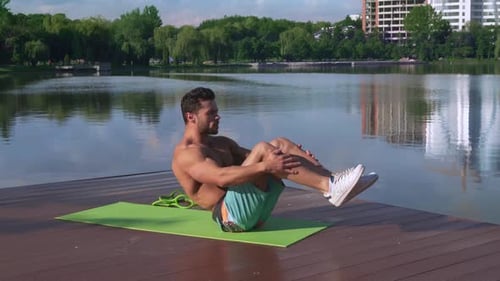 Muscular Man Doing Core Exercises Outdoors by Lake