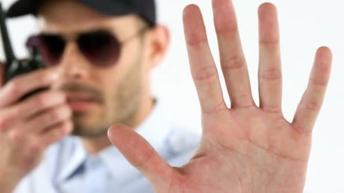 Man Holds Hand Up While Using Walkie-Talkie