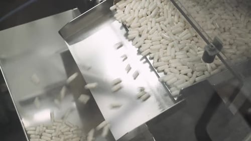 Production of Pharmaceuticals and Drugs Large Number of Capsules in Motion White Tablets on the