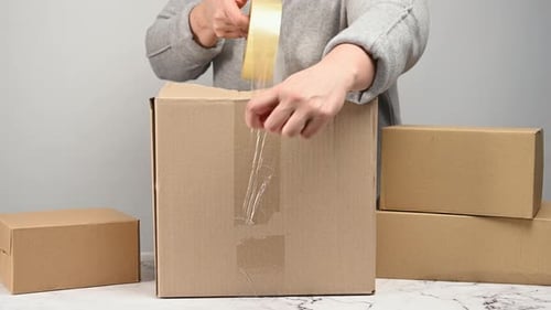 Person Packing Cardboard Box With Tape
