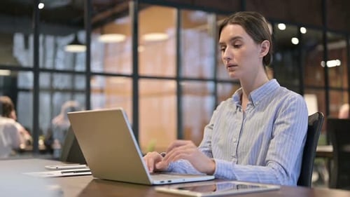 Young Adult Woman Working on Laptop in Office