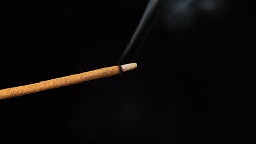 Sandelholzstab mit Räucherstäbchen auf schwarzem Hintergrund