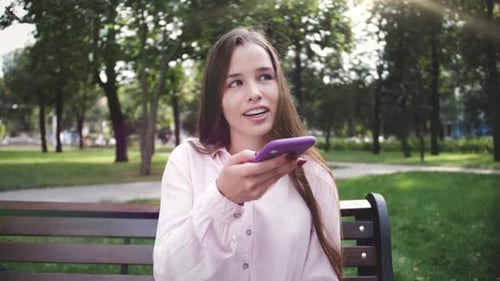 Young Woman Using Phone on Park Bench