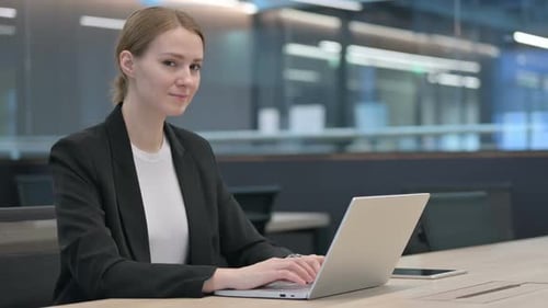 Young Woman Works on Laptop in Modern Office