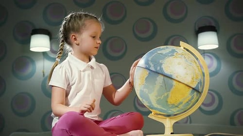 Young Girl Exploring Globe in Her Bedroom