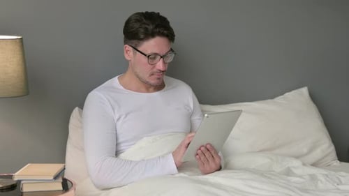 Man Sitting in Bed Using Tablet
